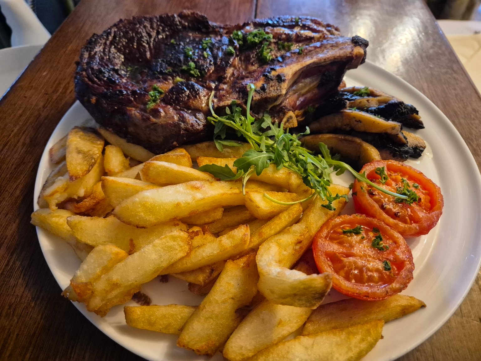 Grilled rib-eye steak with chips and grilled tomatoes