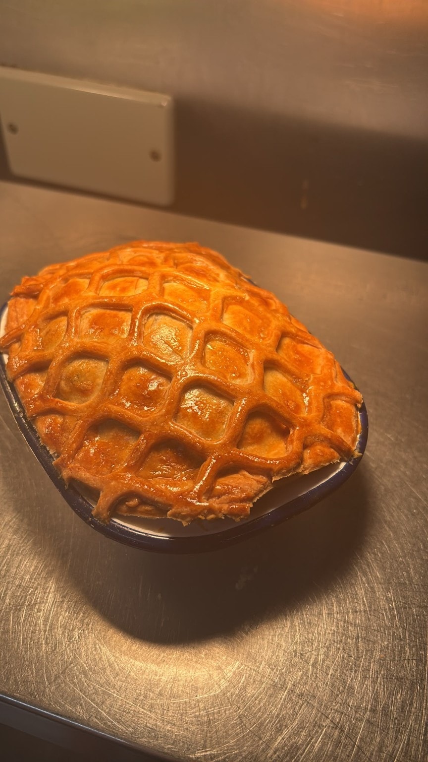 A single golden lattice-top homemade pie in a blue enamel dish